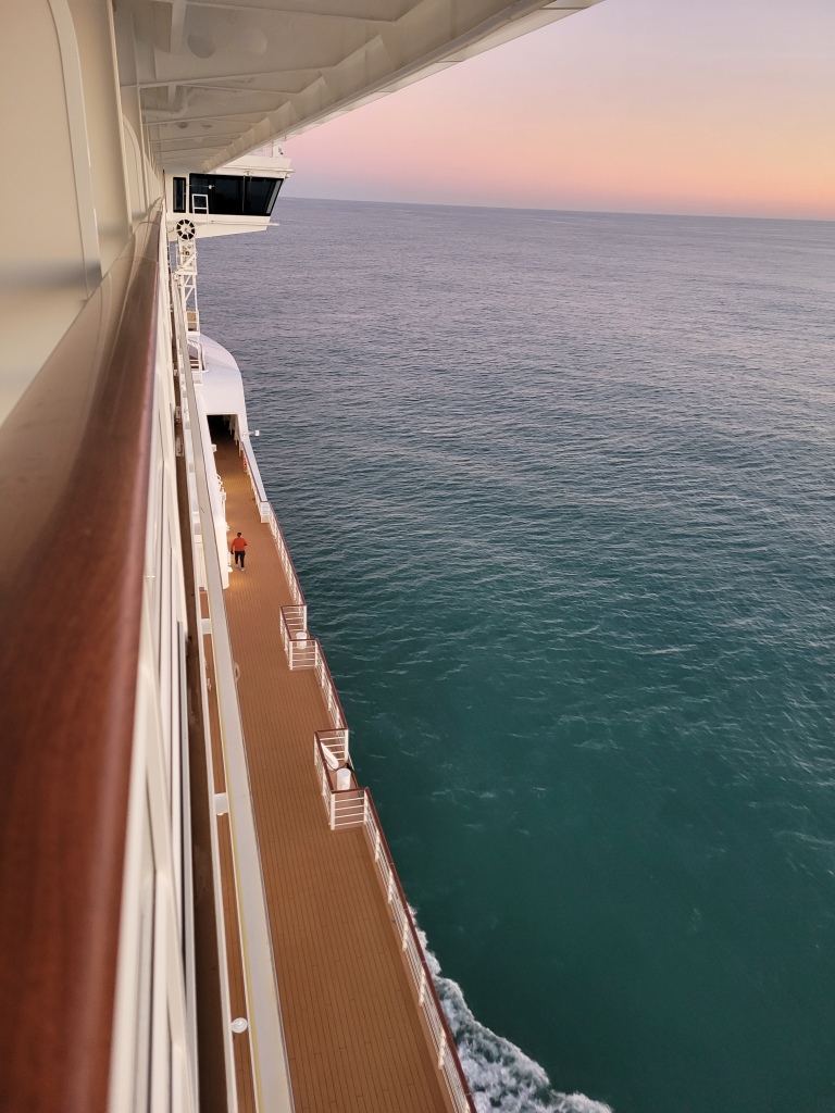 disney wish sailing through open water of the atlantic ocean. the waves are calm and it's nearing sunset